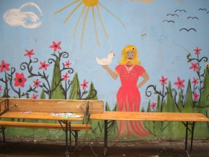 Ein Wandbild zeigt eine blonde Frau mit Bart und Friedenstaube.